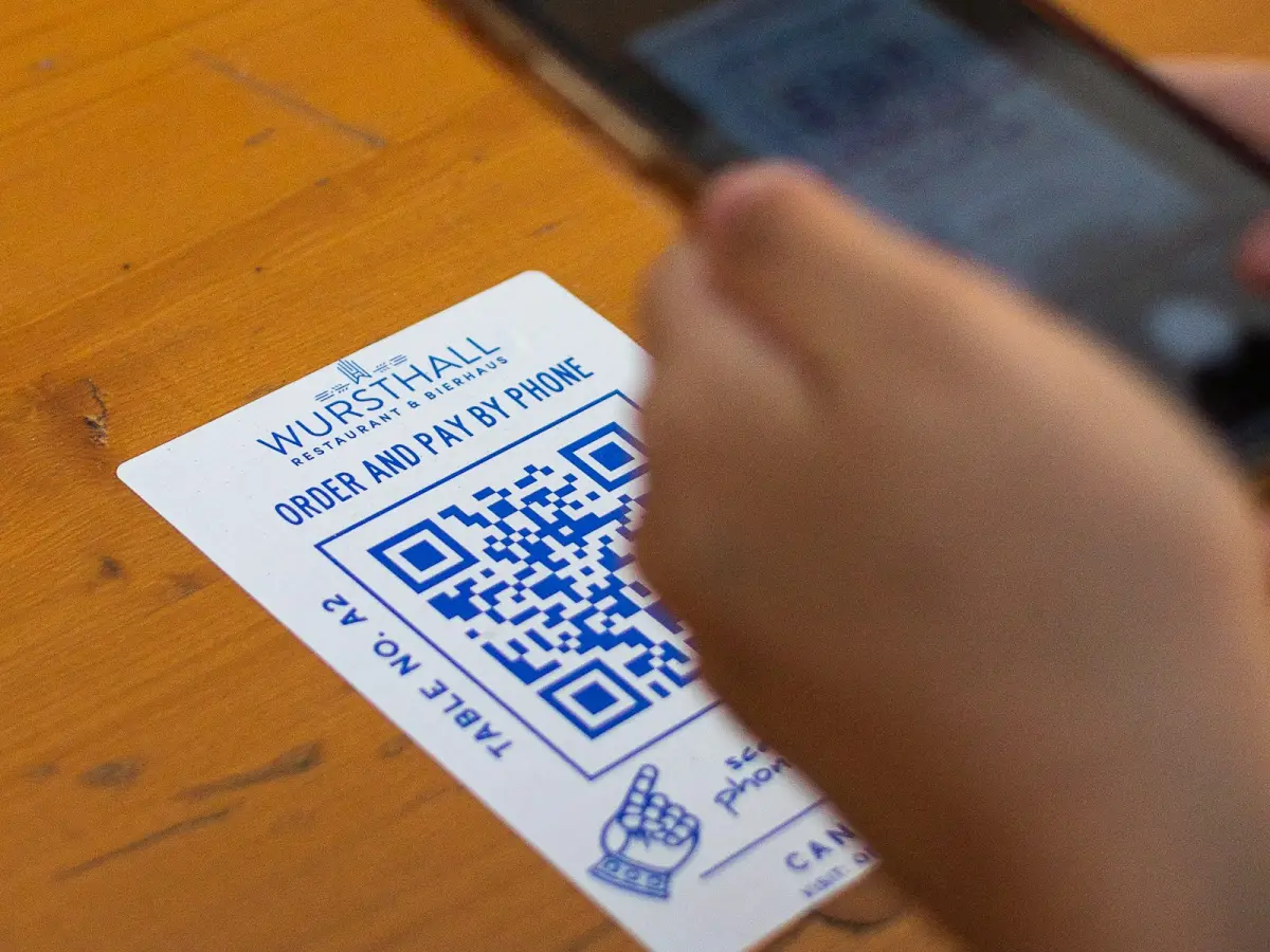 QR-skilt på et bord og en hånd med telefon